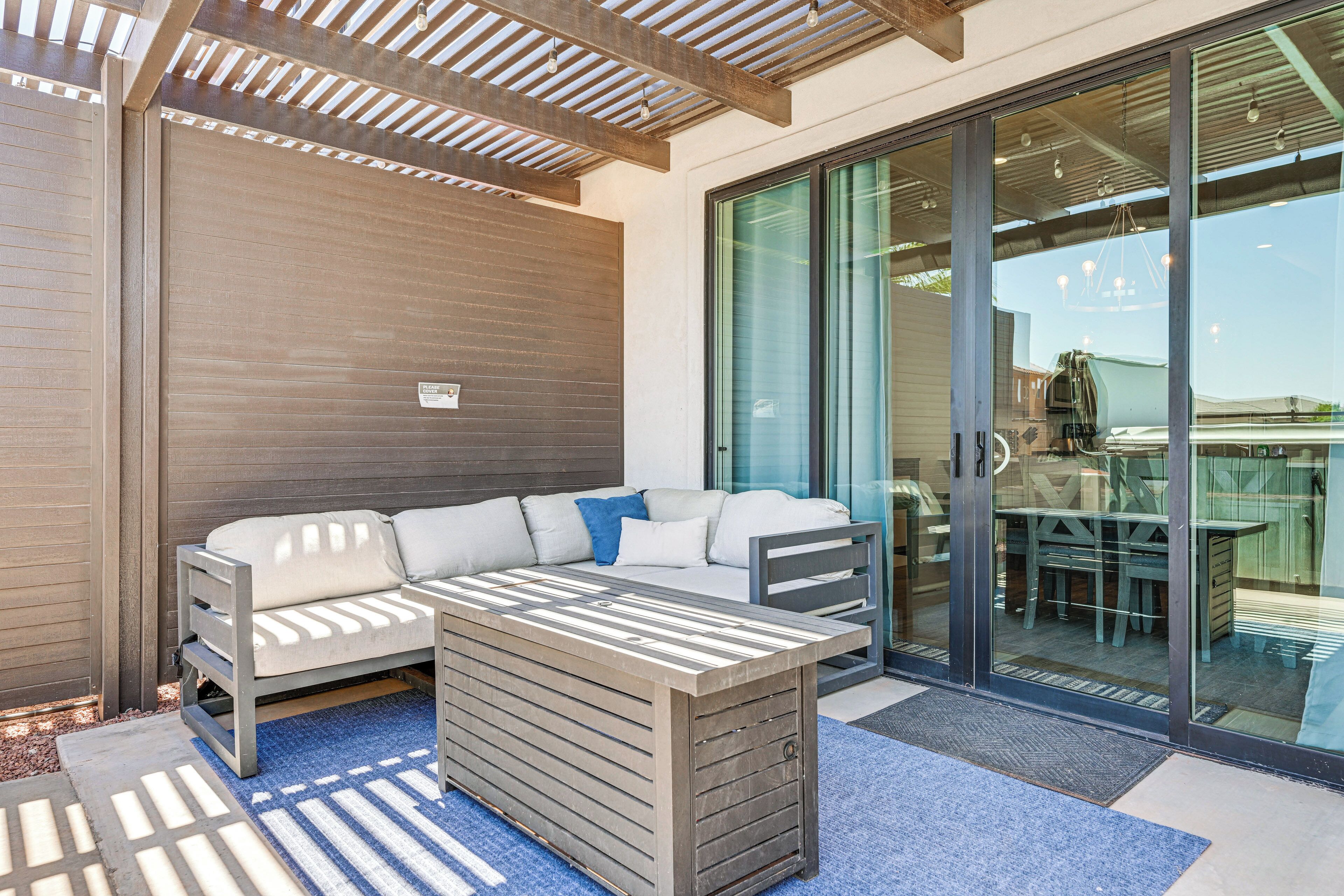 An outdoor seating area with a sofa and a table, a sliding glass door leading to a patio, and a ceiling with wooden beams.