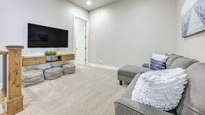 Una sala de estar moderna con un televisor de pantalla plana, un sofá gris y una puerta blanca.