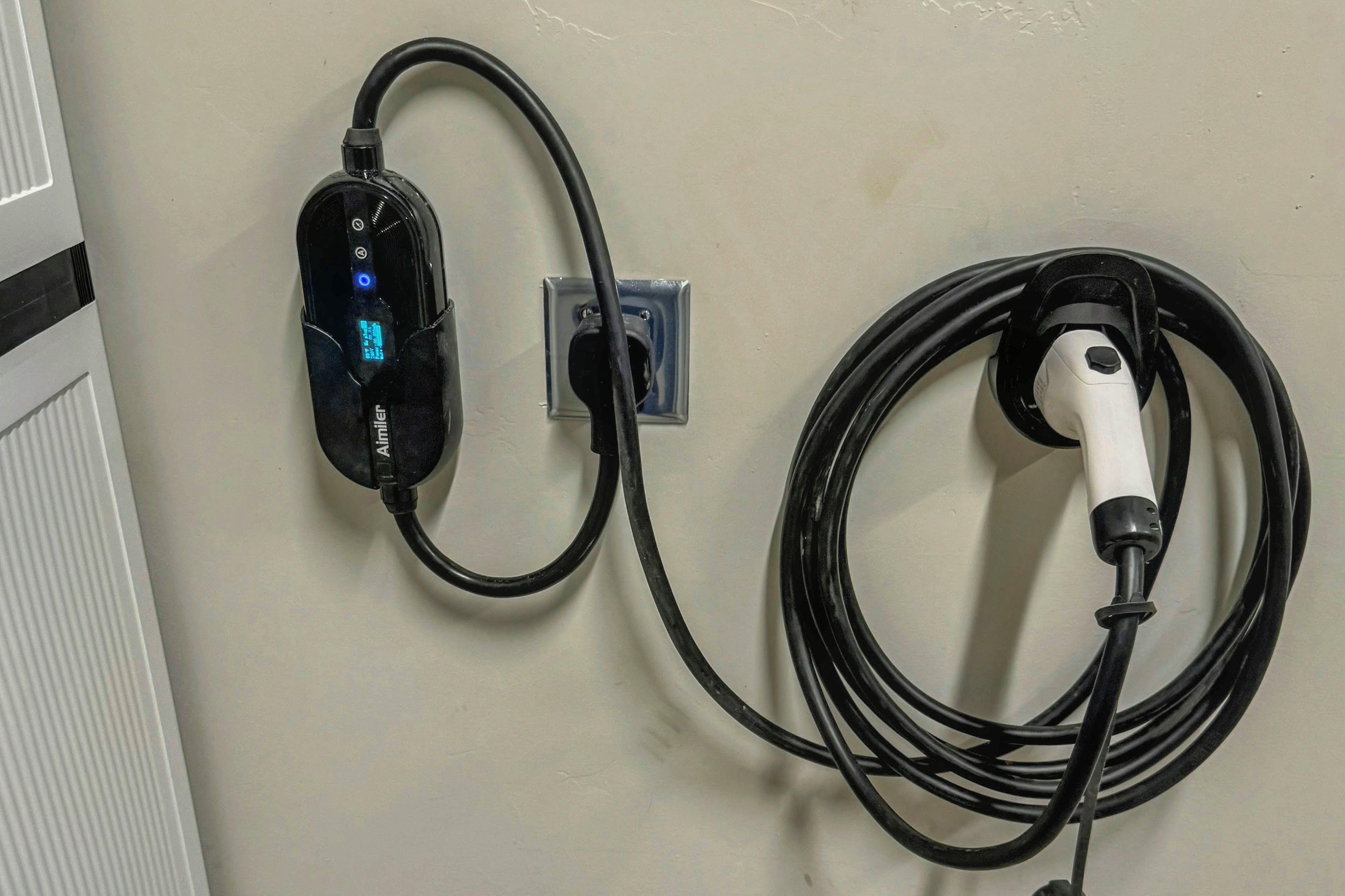 A wall-mounted power outlet with a charging station and a coiled power cord.