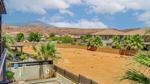 Un barrio residencial con casas, un patio de arena y montañas al fondo.