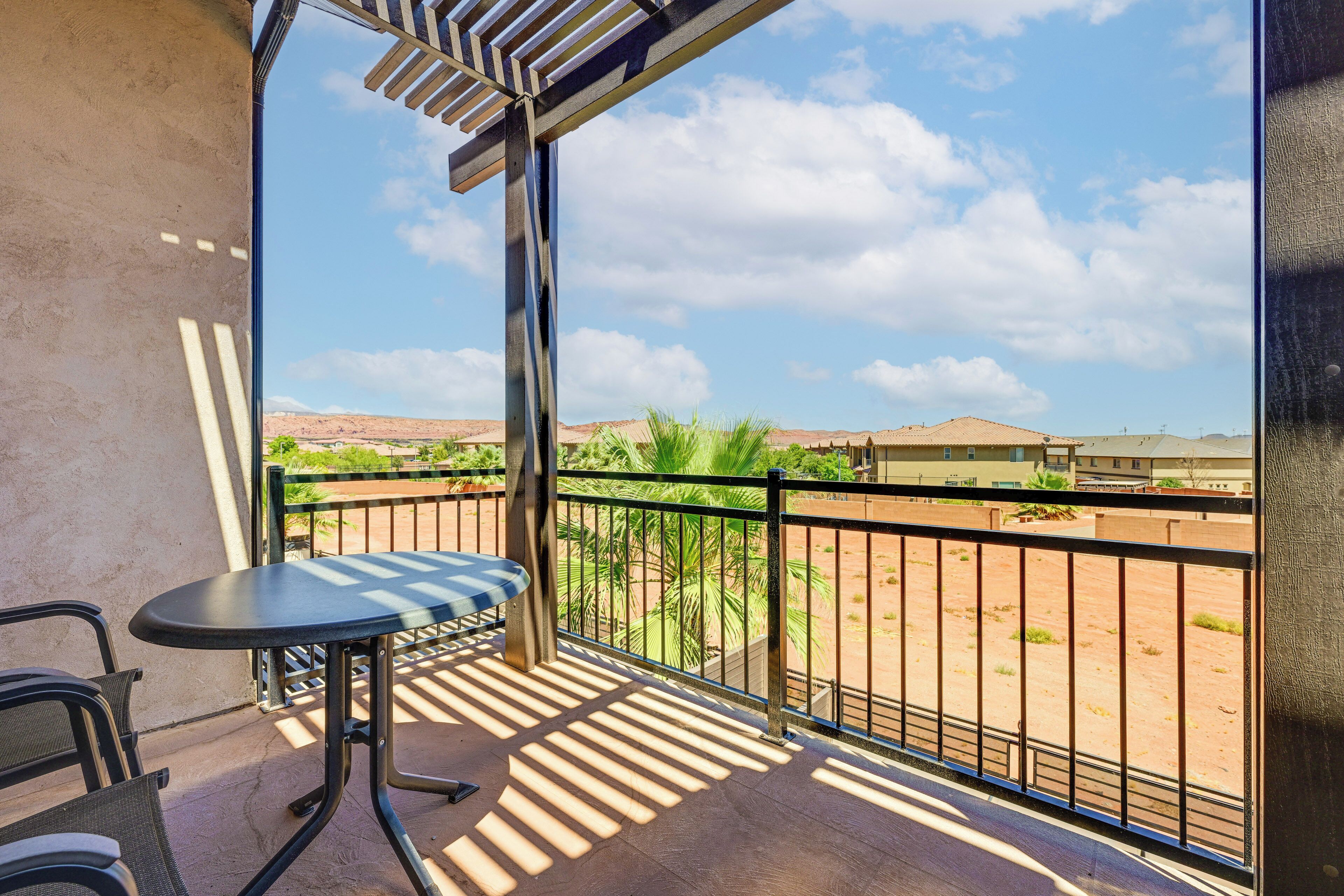 A balcony with a table and chairs, a view of a desert landscape, and a clear sky.