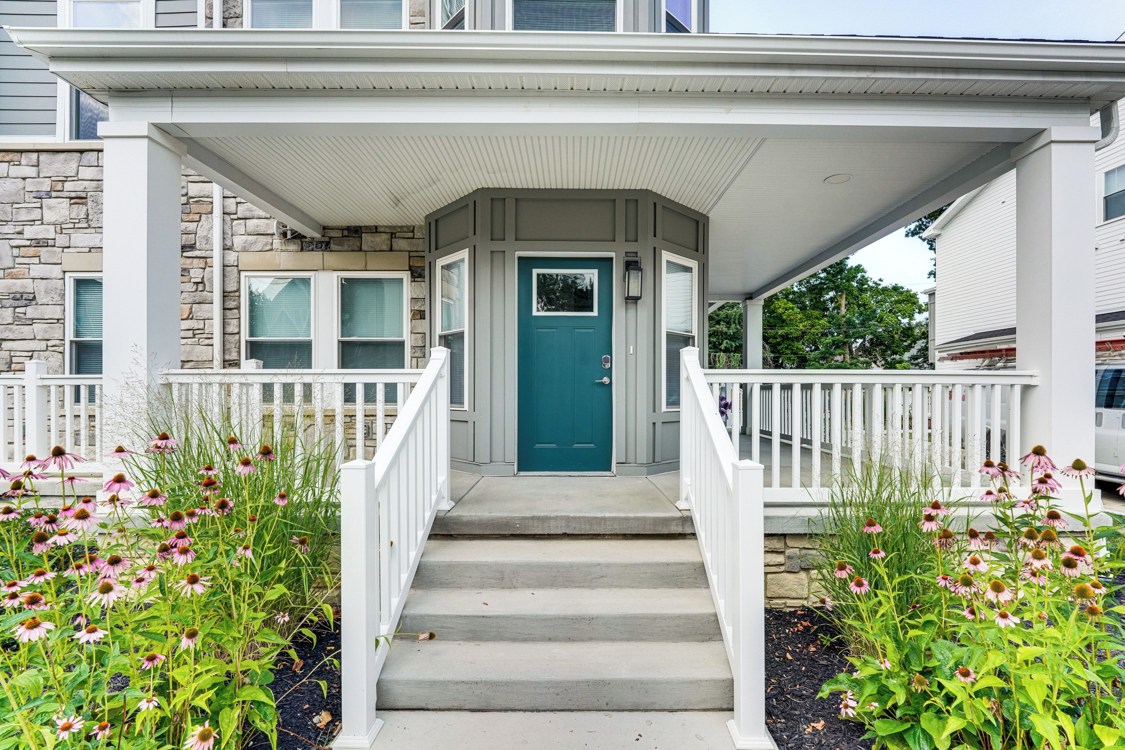 A residential entryway with a front door, a covered porch, and a stone wall.