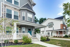 A two-story residential building with a front porch, stone foundation, and a blue door. - Walk to Cleveland Clinic! Contemporary Townhome (Cleveland)