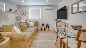Ein modernes Wohnzimmer mit einer Couch, einem Glastisch und einem an der Wand befestigten Fernseher.