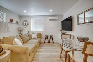 Ein modernes Wohnzimmer mit einer Couch, einem Glastisch und einem an der Wand befestigten Fernseher.