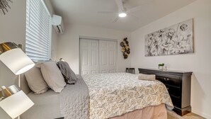 Ein Schlafzimmer mit Bett, Nachttischlampe, Schminktisch und Deckenventilator.