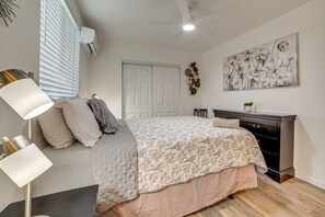 Ein Schlafzimmer mit Bett, Nachttischlampe, Schminktisch und Deckenventilator.