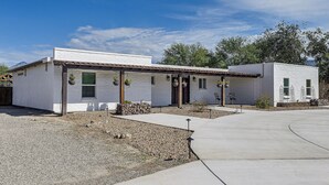 A two-story building with a white exterior, a covered porch, and a gravel driveway. - 7 Mi to Saguaro Natl Park! Mtn-view Haven w/ Pool (Tucson)