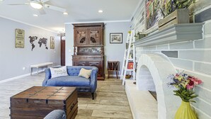 A living room with a blue sofa, wooden cabinet, and a fireplace. - 7 Mi to Saguaro Natl Park! Mtn-view Haven w/ Pool (Tucson)