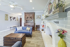 A living room with a blue sofa, wooden cabinet, and a fireplace. - 7 Mi to Saguaro Natl Park! Mtn-view Haven w/ Pool (Tucson)