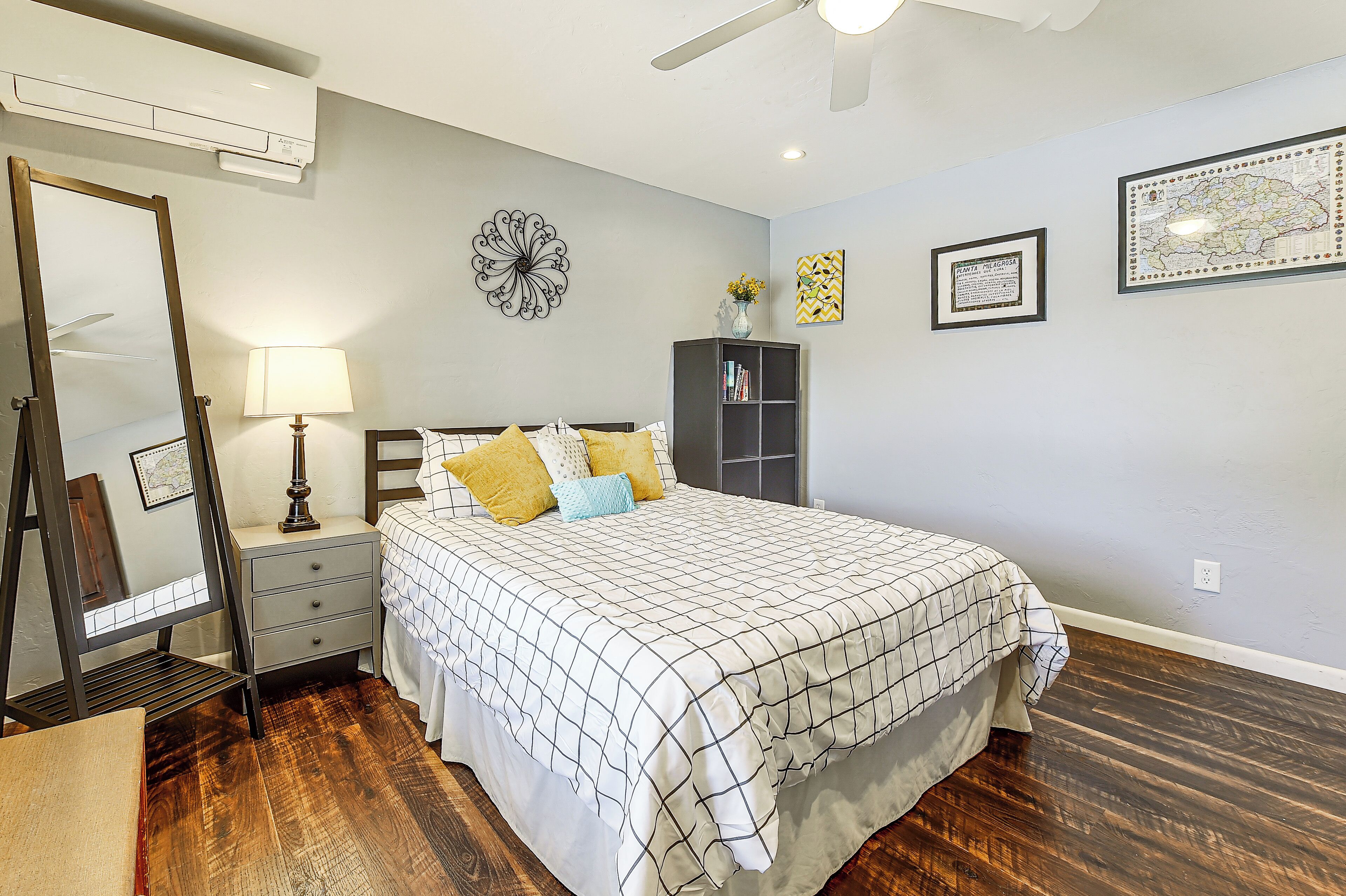 Um quarto com cama, mesa de cabeceira, cômoda e espelho.