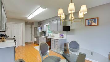 A modern kitchen with white cabinets, a stainless steel refrigerator, and a built-in oven.