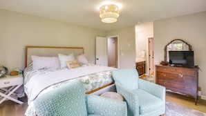 Quarto com cama, mesa de cabeceira, abajur, cômoda e televisão.