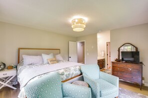 Ein Schlafzimmer mit Bett, Nachttisch, Lampe, Kommode und Fernseher.