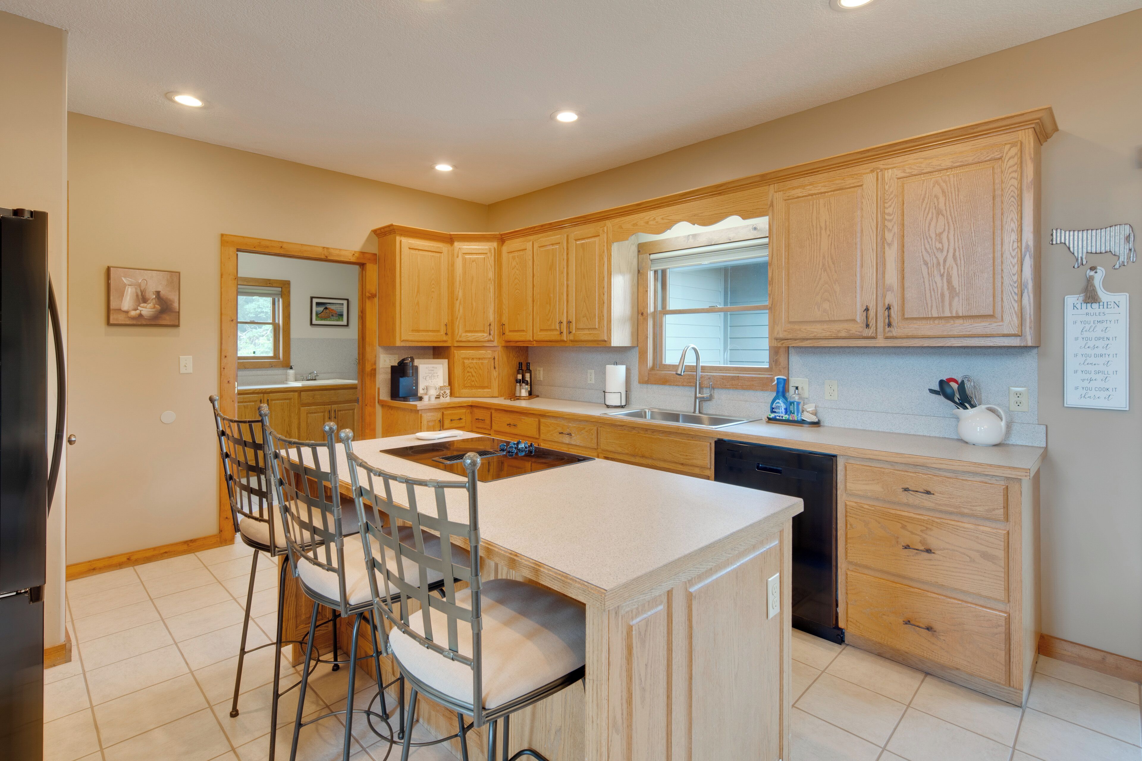A modern kitchen with wooden cabinets, a central island, bar stools, and a dishwasher.