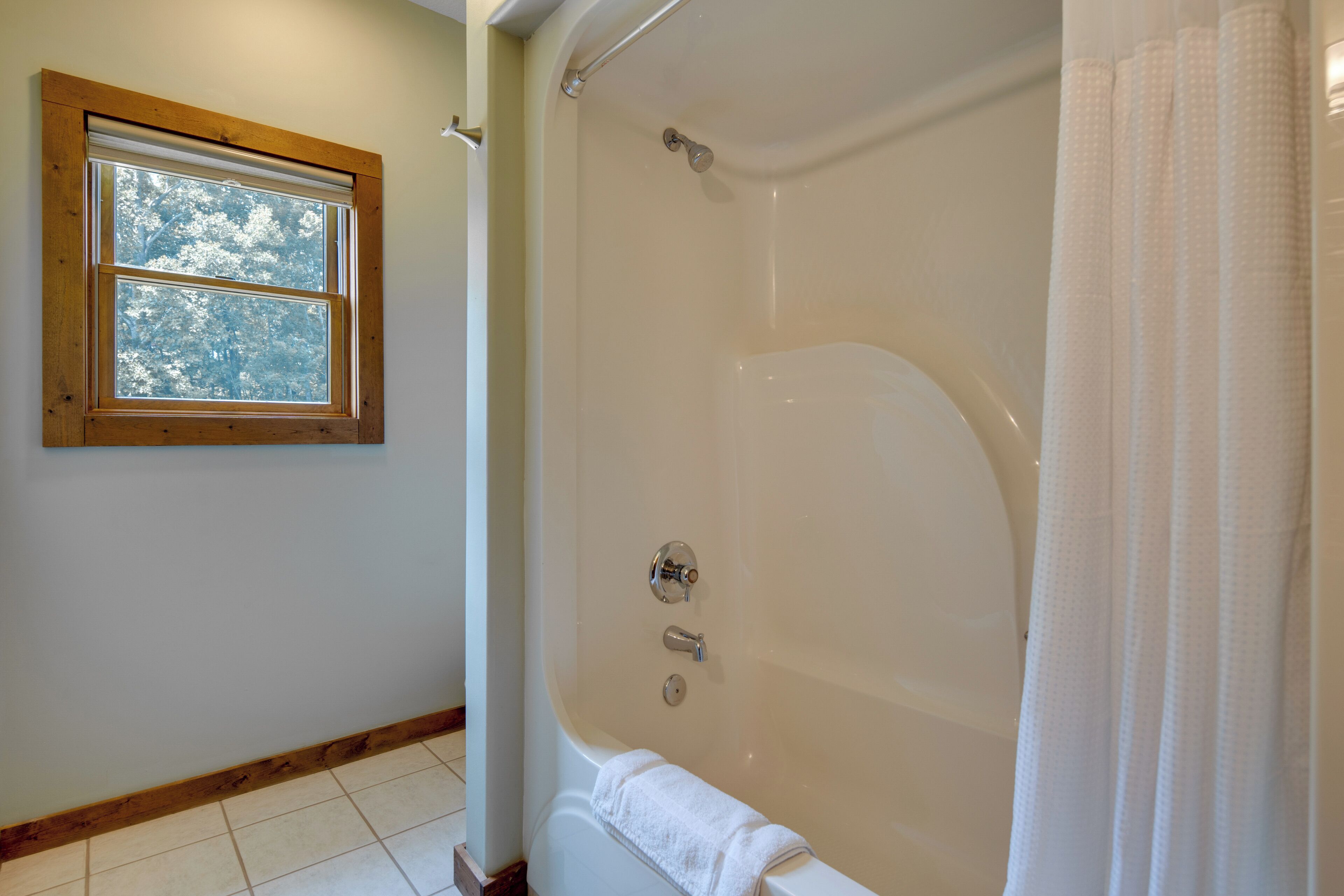 A bathroom with a bathtub, a window, and a shower curtain.