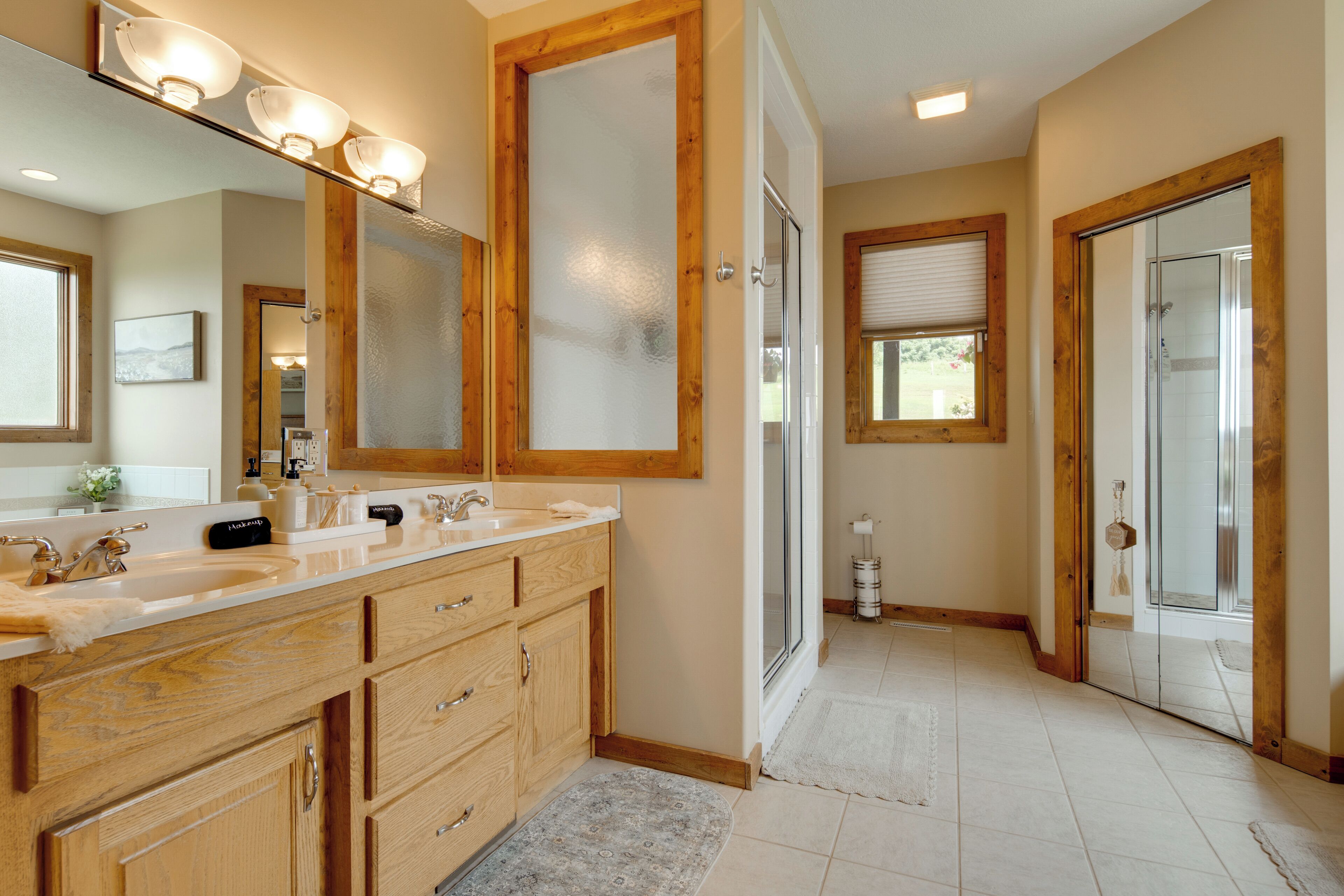 A bathroom with a large mirror, vanity with a sink, and a shower area.