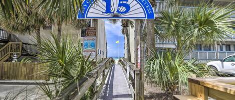 A wooden boardwalk leading to a beach entrance with a sign reading "15 Public Beach Access".