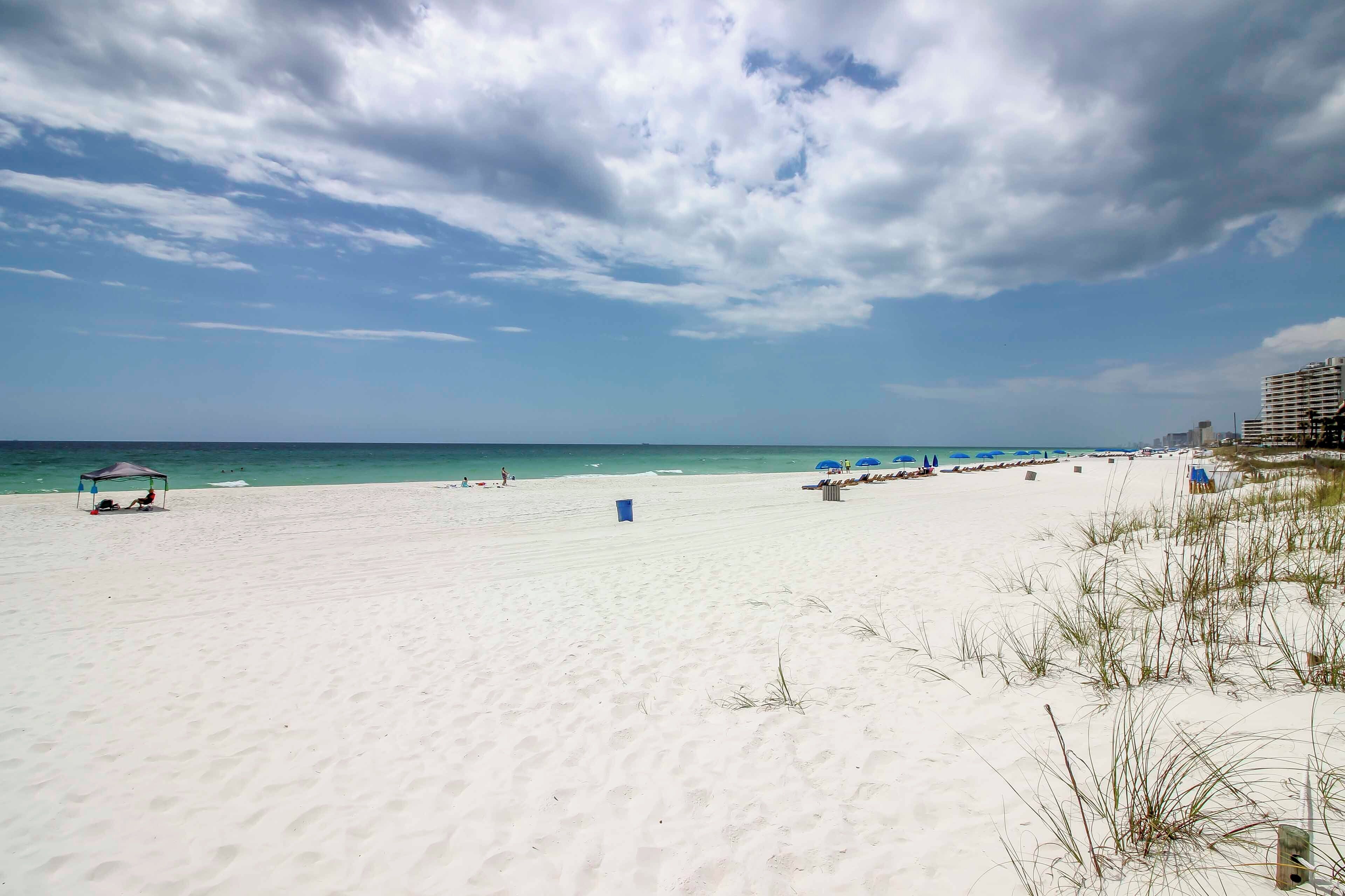 A beach with a clear sky, a sandy shore, and a few beach umbrellas.