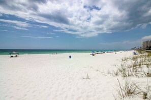 A beach with a clear sky, a sandy shore, and a few beach umbrellas. - Pool Days + Beach Strolls! Ground-floor PCB Condo (Panama City Beach)
