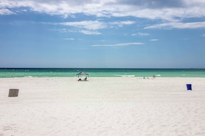 A beach with a clear sky, calm sea, and a few people in the distance. - Pool Days + Beach Strolls! Ground-floor PCB Condo (Panama City Beach)