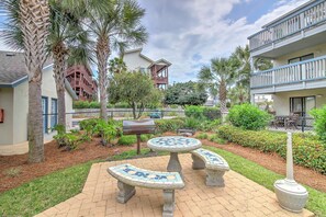 A courtyard with a mosaic-tiled bench, palm trees, and a fence. - Pool Days + Beach Strolls! Ground-floor PCB Condo (Panama City Beach)