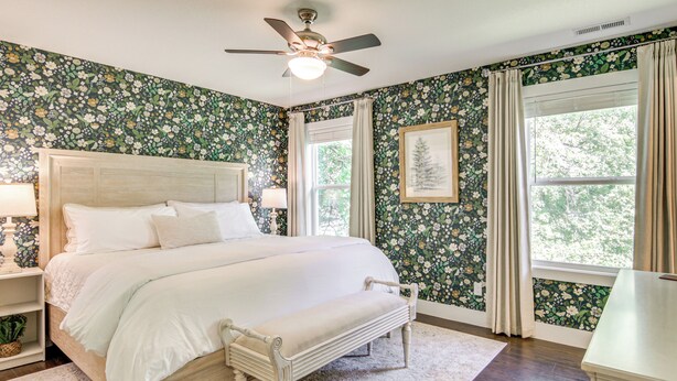 A bedroom with a wooden bed, a ceiling fan, a window with curtains, and floral wallpaper. - Walk to Dtwn Waynesville! Dual Mtn Havens w/ Decks (Waynesville)