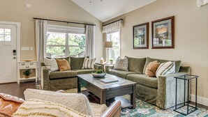 A living room with a sofa, a coffee table, a patterned rug, and two framed pictures on the wall. - Walk to Dtwn Waynesville! Dual Mtn Havens w/ Decks (Waynesville)