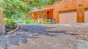 Ein Holzhaus mit überdachter Veranda, einer Garage und einem Schotterweg.