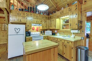 A cabin-style kitchen with wooden cabinets, a refrigerator, stove, microwave, and a sink. - Rustic Cabin w/ Phoenix Mtn Views & Trail Access! (Lansing)