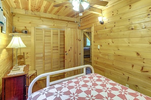 A wooden interior with a bed, a nightstand, a lamp, and a ceiling fan. - Rustic Cabin w/ Phoenix Mtn Views & Trail Access! (Lansing)