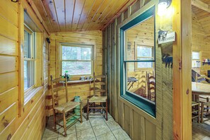 A wooden cabin interior with a dining area, a window with a 'Welcome' sign, and a view of the forest outside. - Rustic Cabin w/ Phoenix Mtn Views & Trail Access! (Lansing)