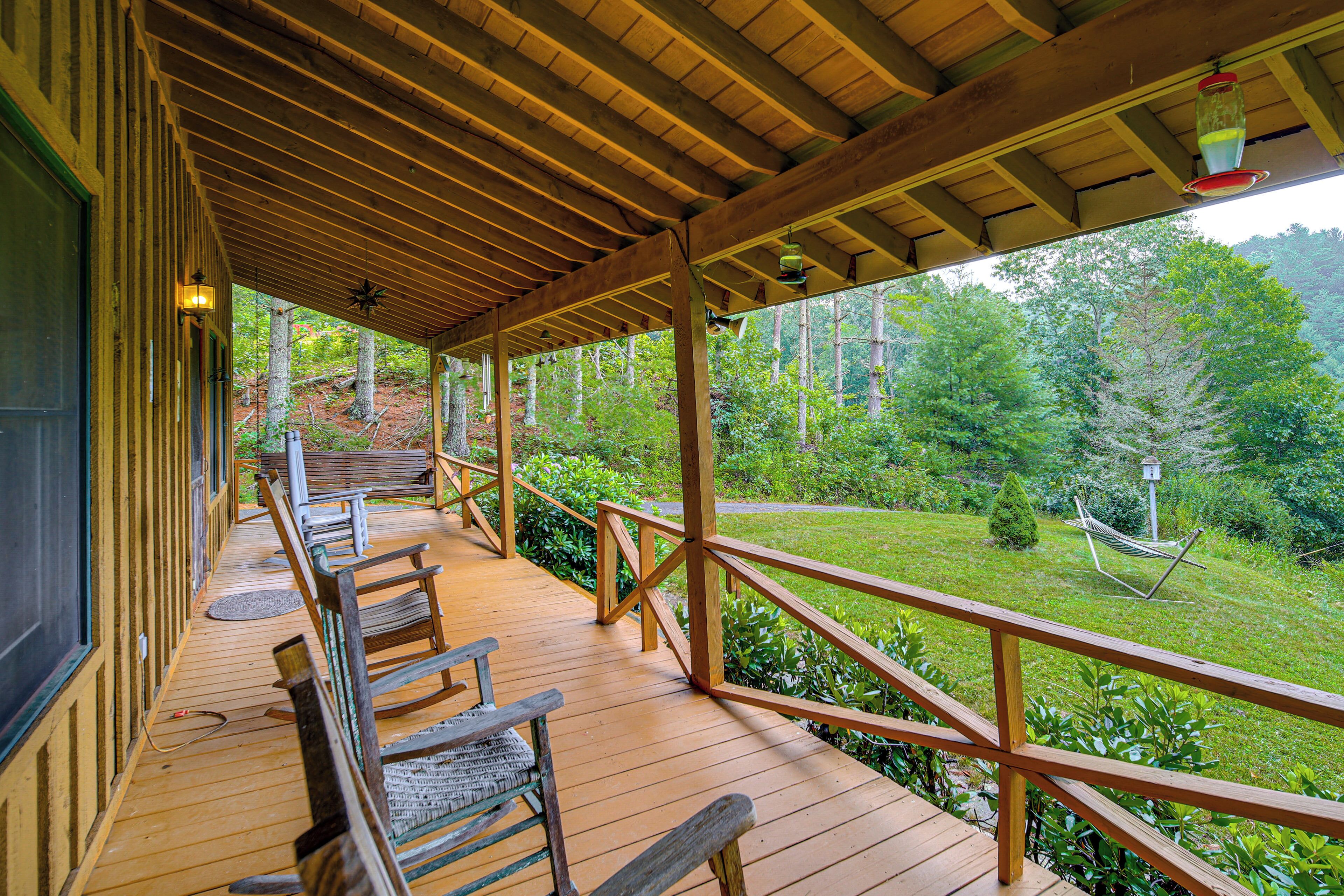 Une terrasse en bois, dotée de bancs et d’une rambarde, qui offre une vue sur une zone boisée.