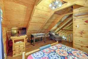 A cozy attic bedroom with a wooden ceiling, a bed, a chair, a table, and a television. - Rustic Cabin w/ Phoenix Mtn Views & Trail Access! (Lansing)