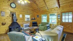 A cabin interior with a fireplace, sofa, television, and a chess table. - Rustic Cabin w/ Phoenix Mtn Views & Trail Access! (Lansing)