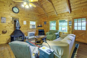 A cabin interior with a fireplace, sofa, television, and a chess table. - Rustic Cabin w/ Phoenix Mtn Views & Trail Access! (Lansing)