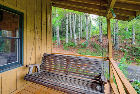 A wooden bench with a chain link backrest, positioned on a porch with a view of a forested area. - Rustic Cabin w/ Phoenix Mtn Views & Trail Access! (Lansing)