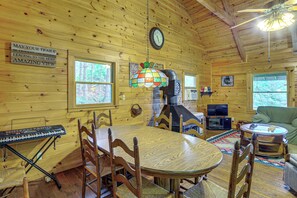 A wooden interior with a dining table, chairs, a clock, a television, and a fireplace. - Rustic Cabin w/ Phoenix Mtn Views & Trail Access! (Lansing)