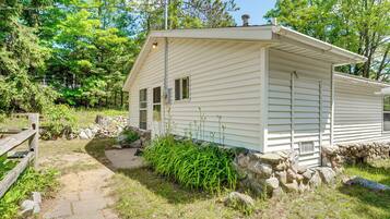 A single-story house with a stone foundation, a wooden deck, and a stone wall.
