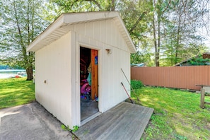 A small shed with a door open, revealing a cluttered interior with various items.