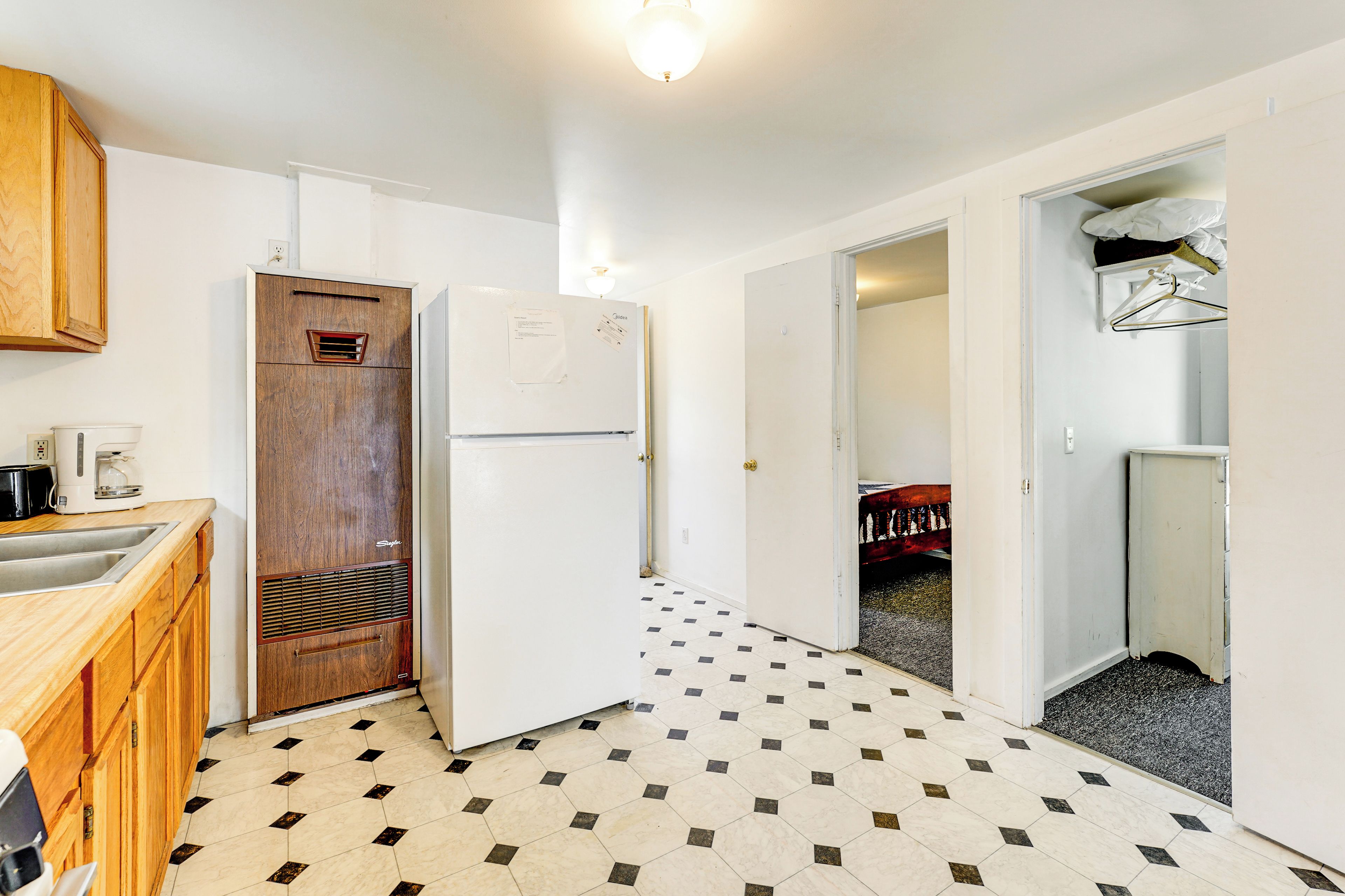 A kitchen with wooden cabinets, a white refrigerator, and a tiled floor.