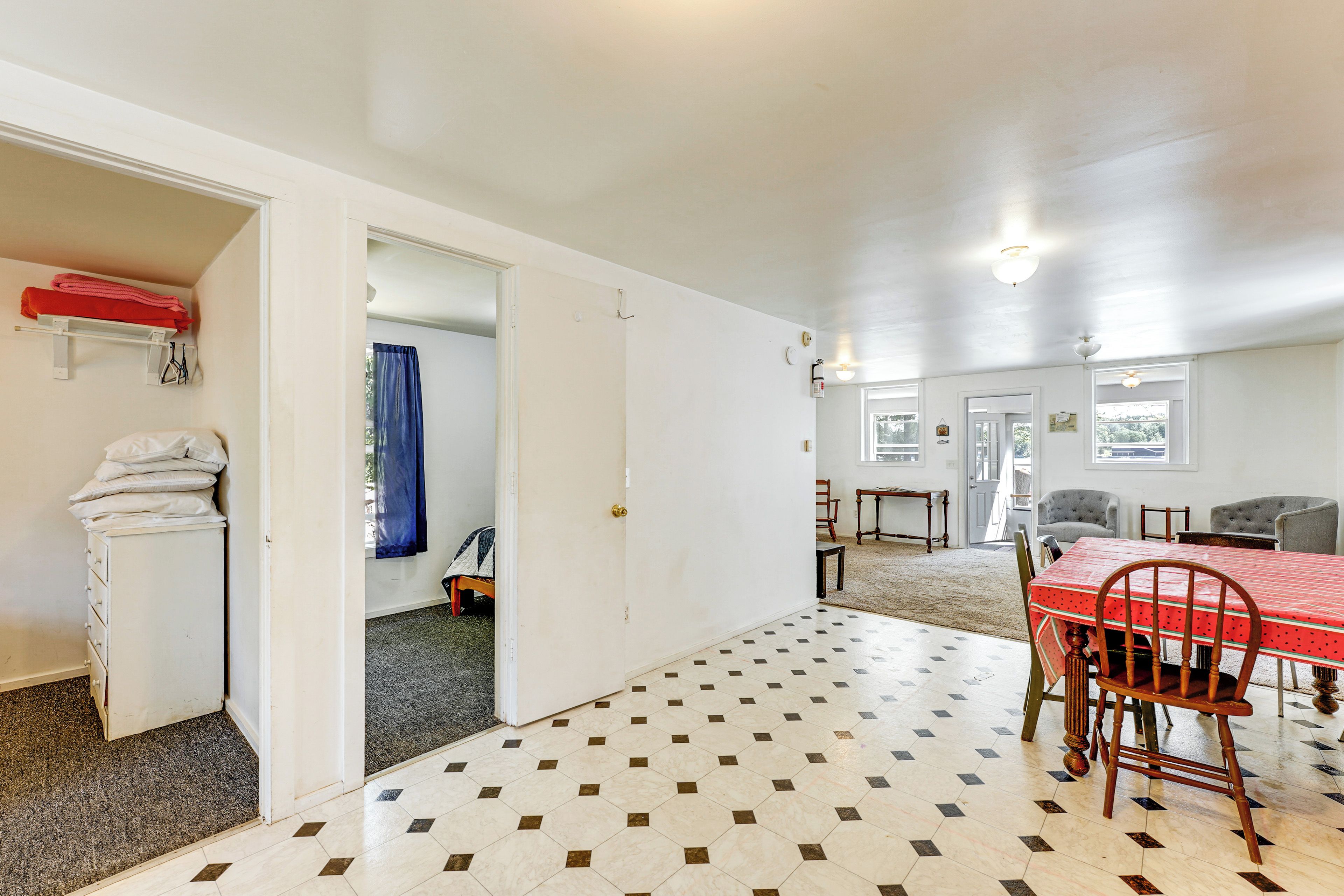 Une pièce comprenant une table à manger, des chaises, une armoire blanche et une nappe rouge.
