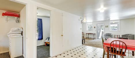 Une pièce comprenant une table à manger, des chaises, une armoire blanche et une nappe rouge.