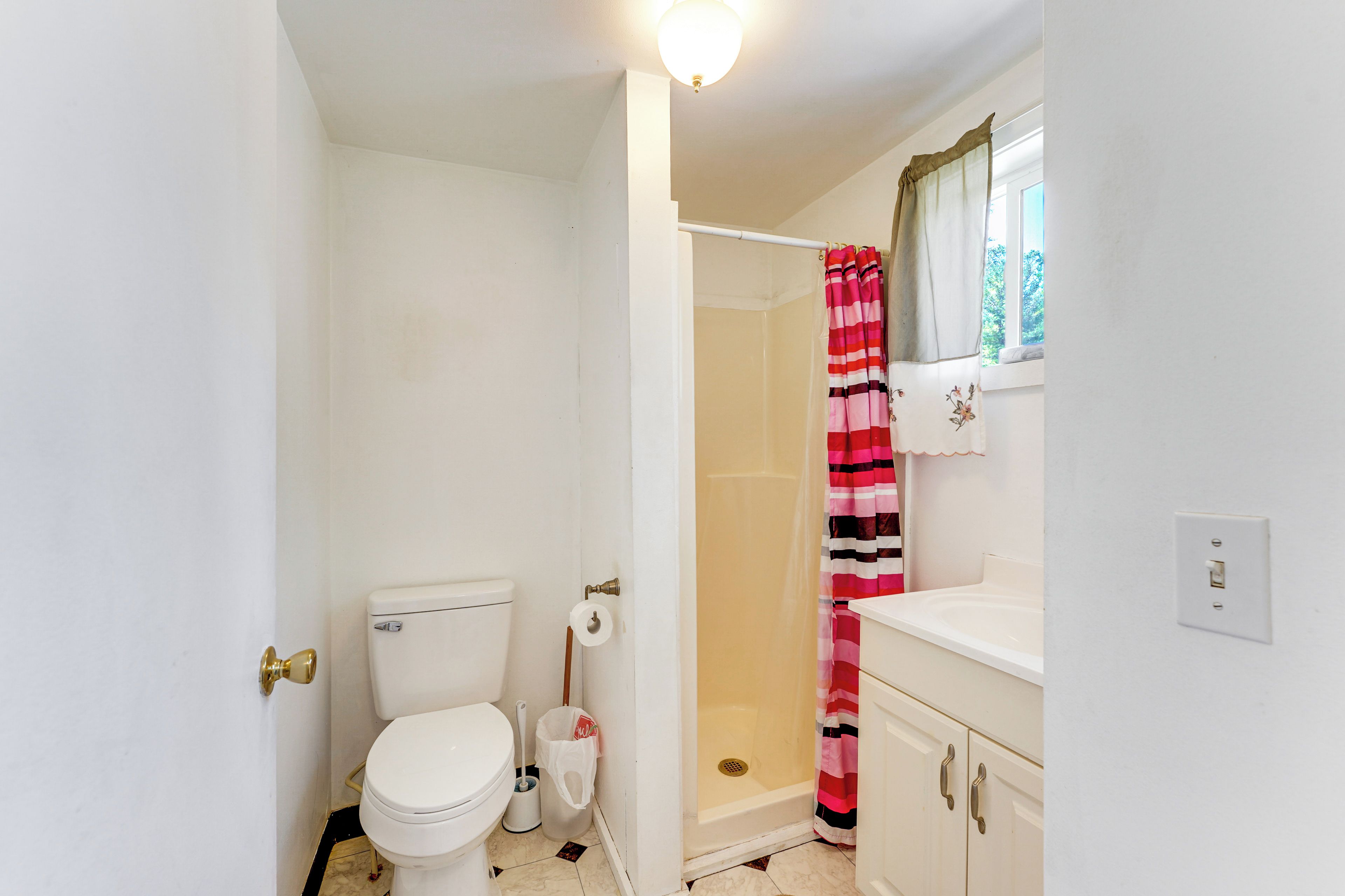 A bathroom with a toilet, shower, and sink.