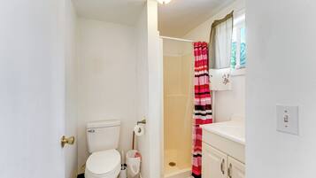 A bathroom with a toilet, shower, and sink.