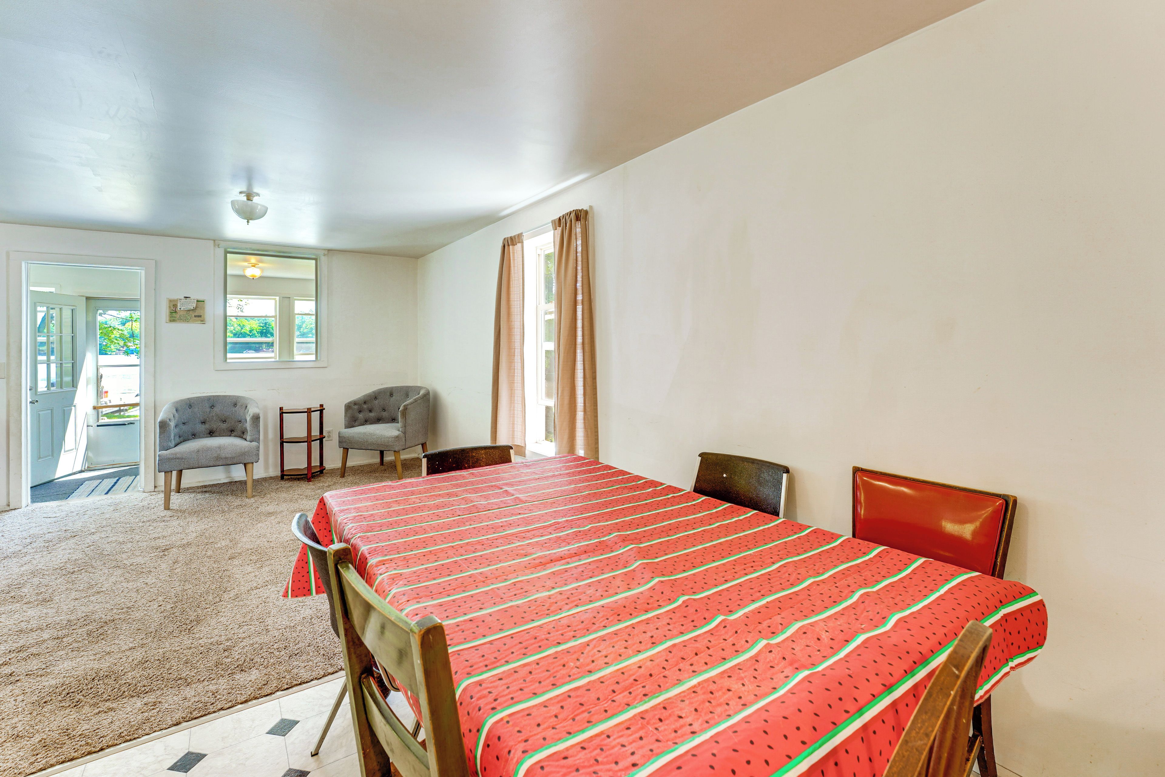 A room with a bed, two chairs, a small table, and a door leading outside.