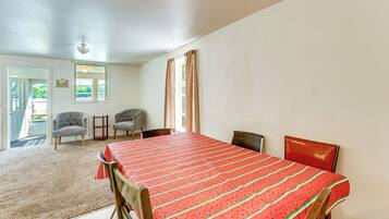 A room with a bed, two chairs, a small table, and a door leading outside.