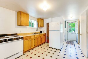 A kitchen with wooden cabinets, a stove, a refrigerator, and a patterned floor. - Waterfront Escape on Bass Lake: Paddle, Fish, Swim (Irons)