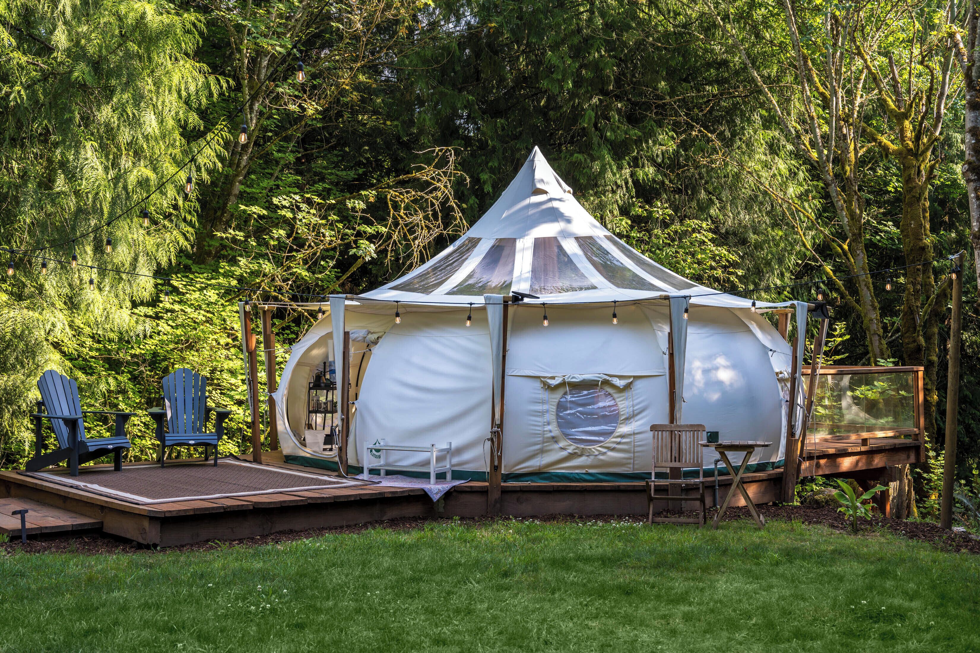 A tent with a platform and seating area, surrounded by trees.
