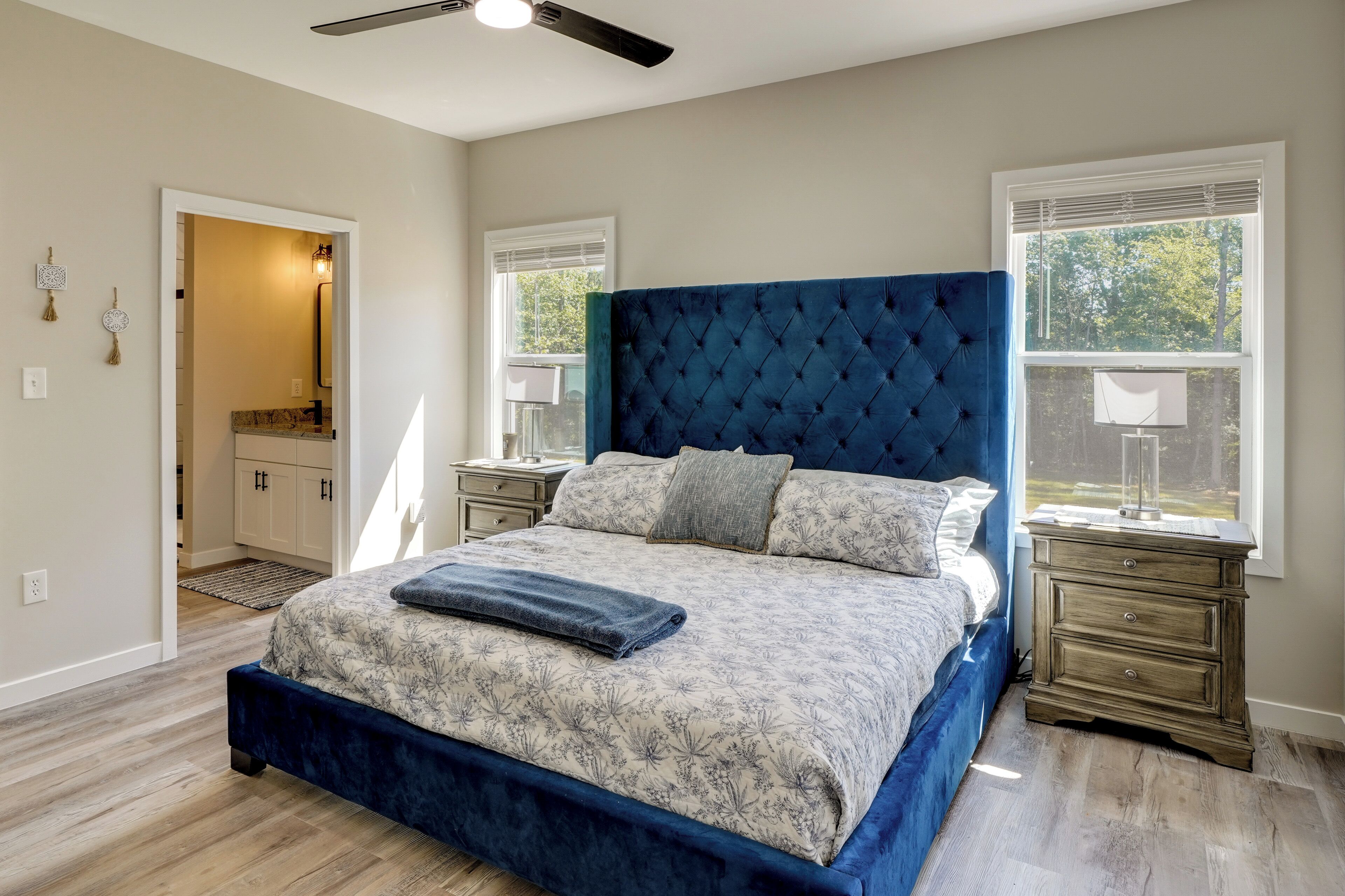 A bedroom with a large bed, a dresser, a mirror, and a ceiling fan.